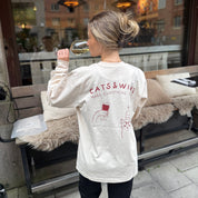 Person wearing a 'Cats & Wine Make Everything Fine' shirt outdoors.